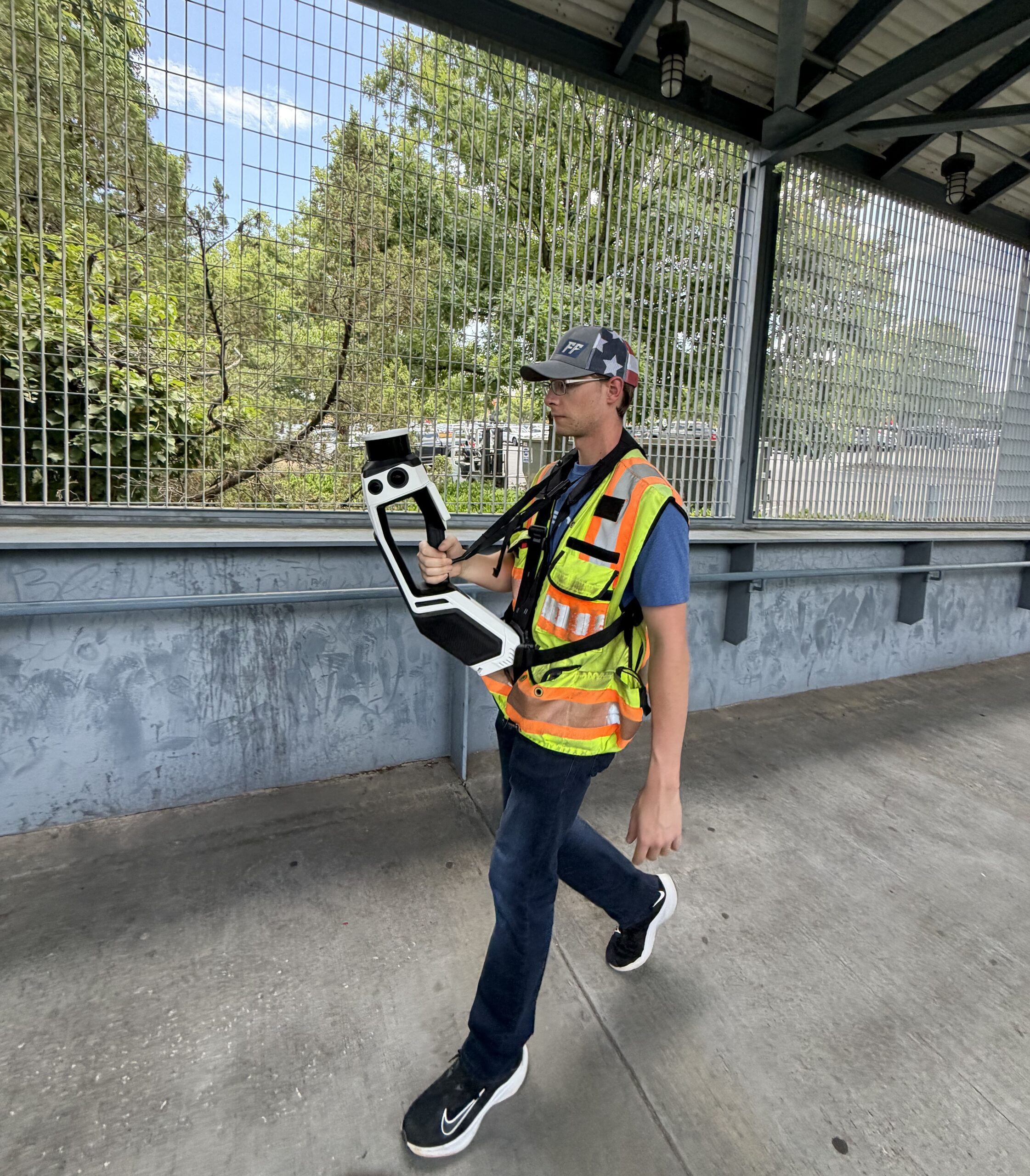 A man with a scanner walking on a bridge